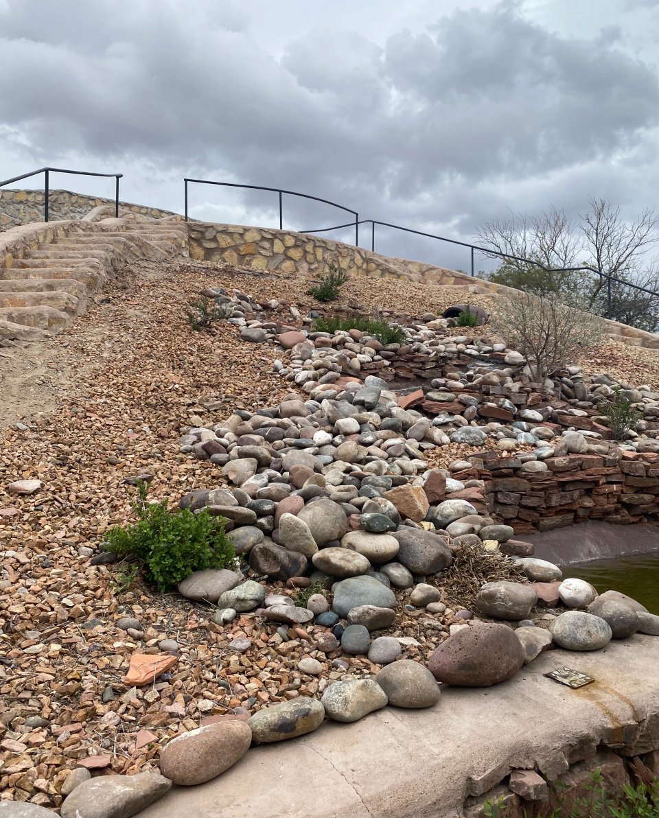 Rock-lined French drain channel carrying water off a sloped Las Cruces yard, installed by Brainard's Greenscapes
