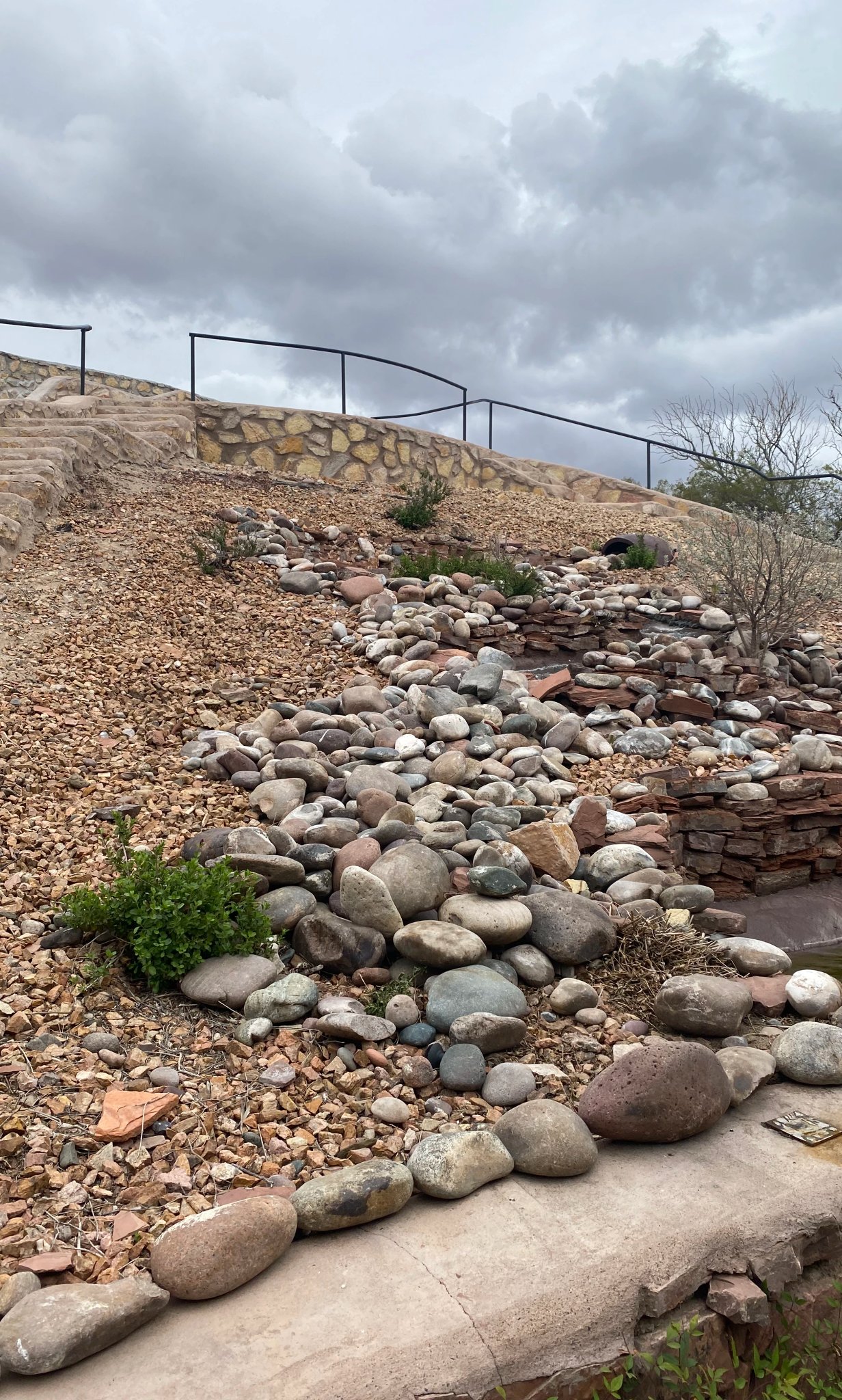 Rock-lined stormwater channel carrying runoff down a graded slope by Brainard's Greenscapes in Las Cruces, NM