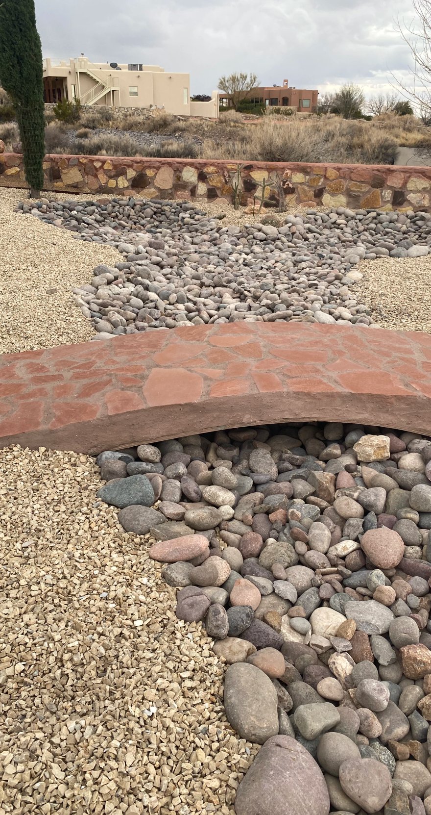 Decorative French drain dry creek bed with flagstone crossing installed by Brainard's Greenscapes in Las Cruces, NM