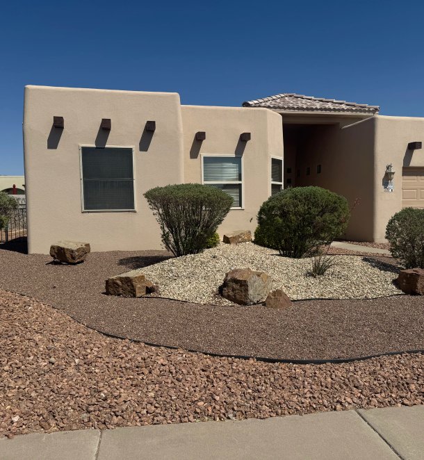 Adobe home with crisp xeriscape of layered gravel and accent boulders